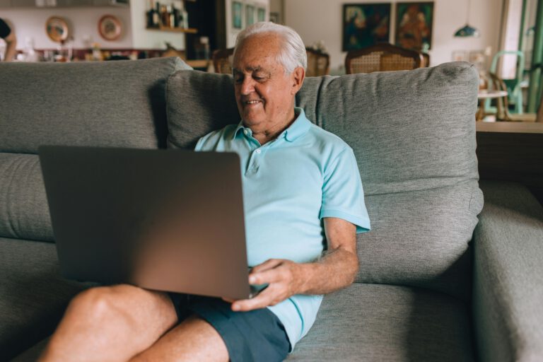 An older man sitting on a couch with a laptop